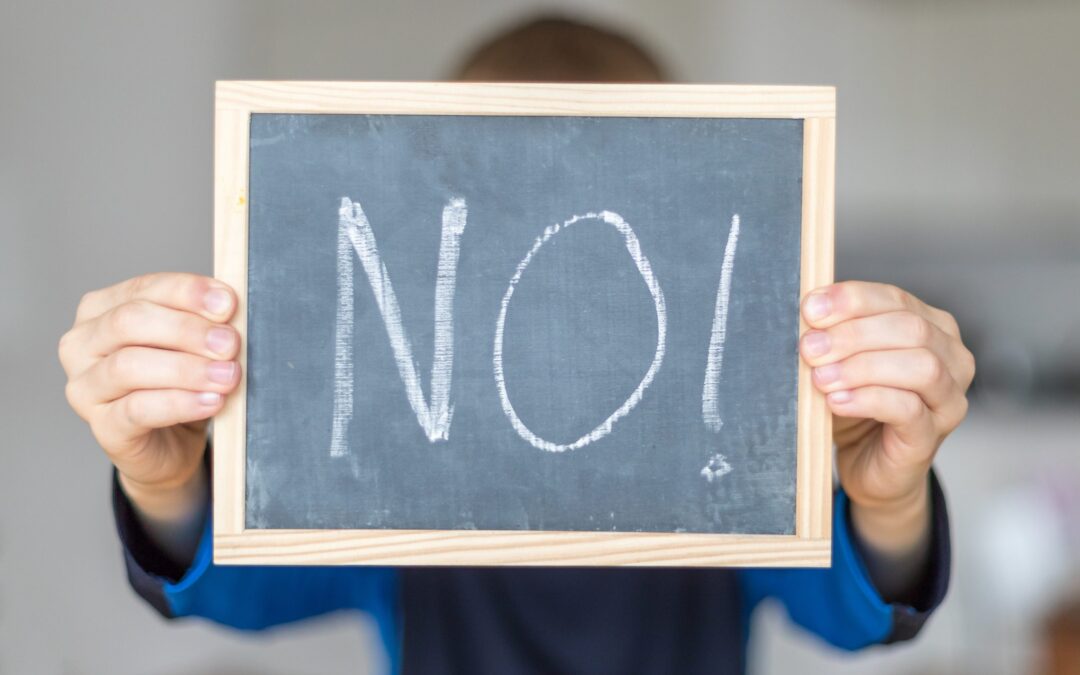 boy holds blackboard with NO letters to demonstrate school refusal disorder